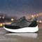 A black low top sneaker with a combination of nappa and suede materials, featuring a lace-up closure with velcro, and a white sole.